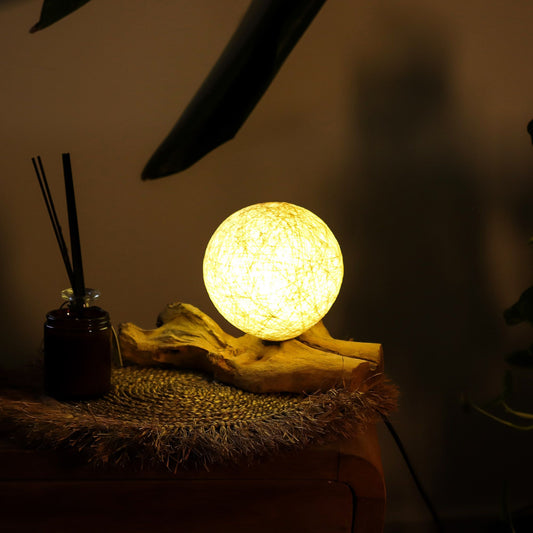 Cream cotton-wrapped sphere glowing gently atop twisted driftwood base