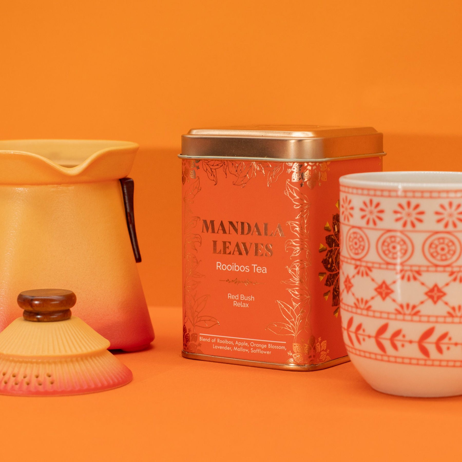Tea canister and mug with mandala leaf design on an orange background