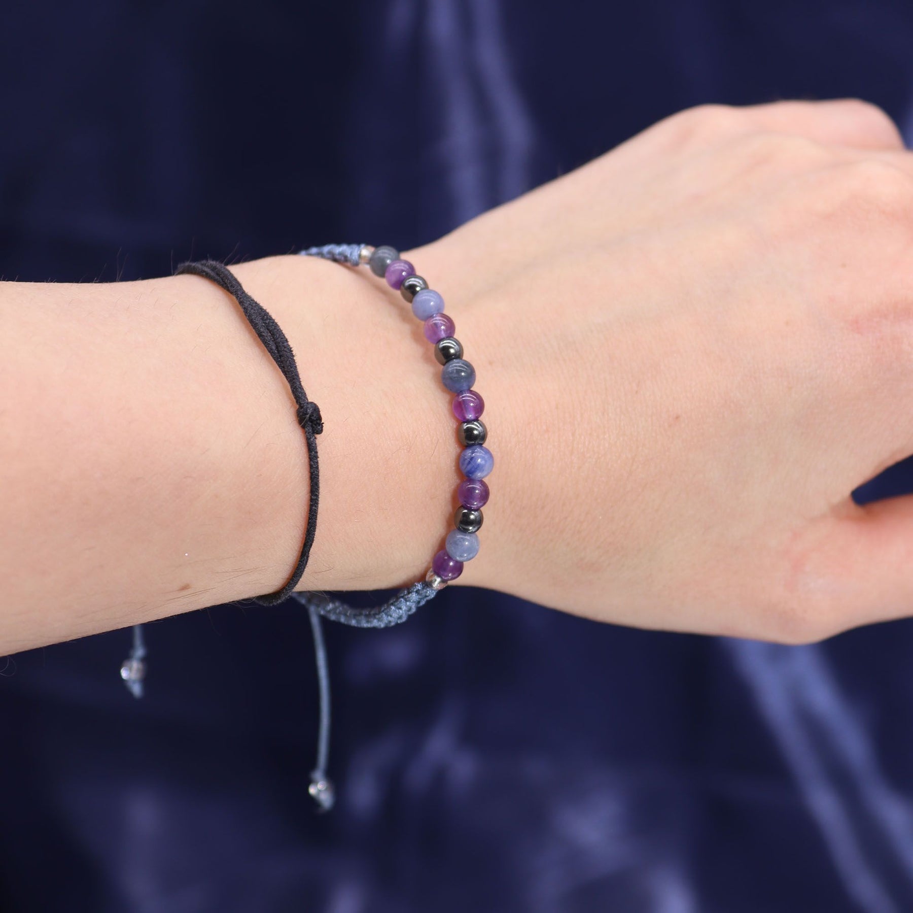 Close-up of a wrist wearing two beaded bracelets against a dark background