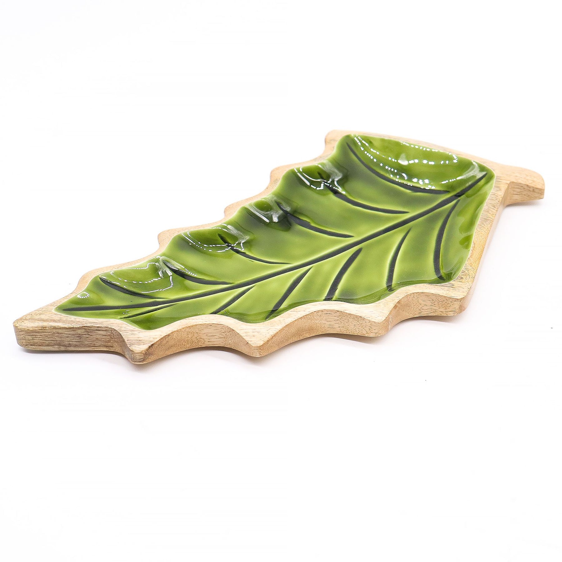 Large leaf-shaped mango wood bowl with rich green enamel inside, filled with pine cones and candles on autumn table setting