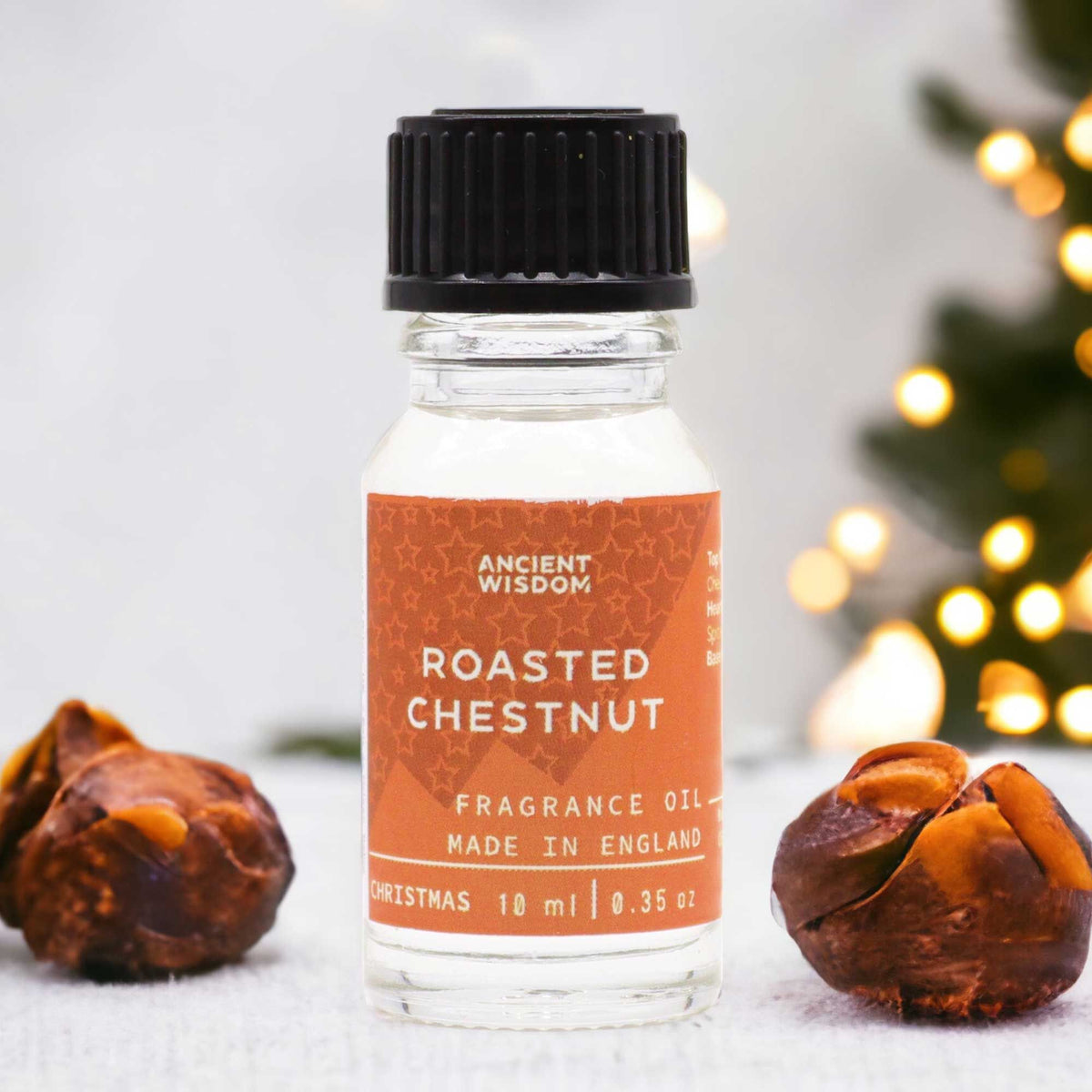 10ml amber glass bottle of Roasted Chestnut fragrance oil with chestnuts and glowing fireplace in cosy winter background