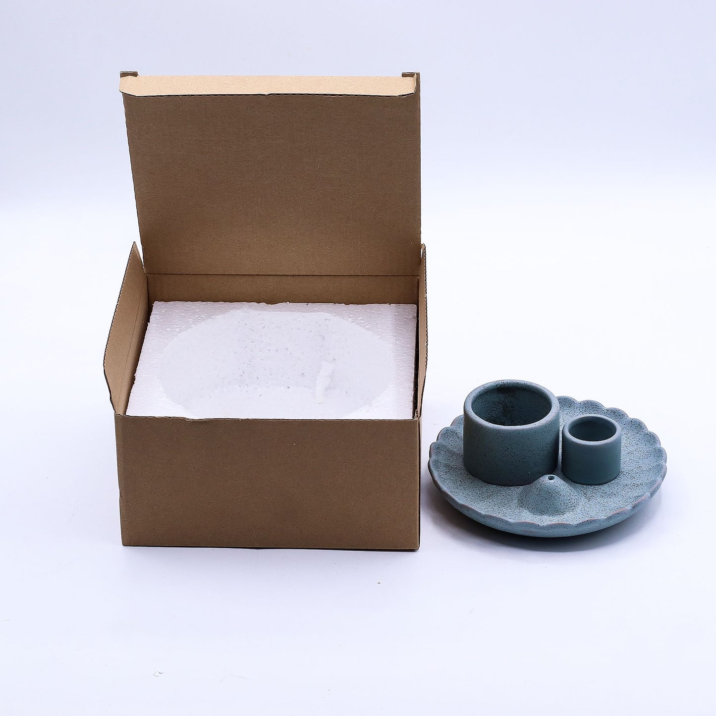 Blue ceramic cup and saucer next to an open cardboard box with packing material