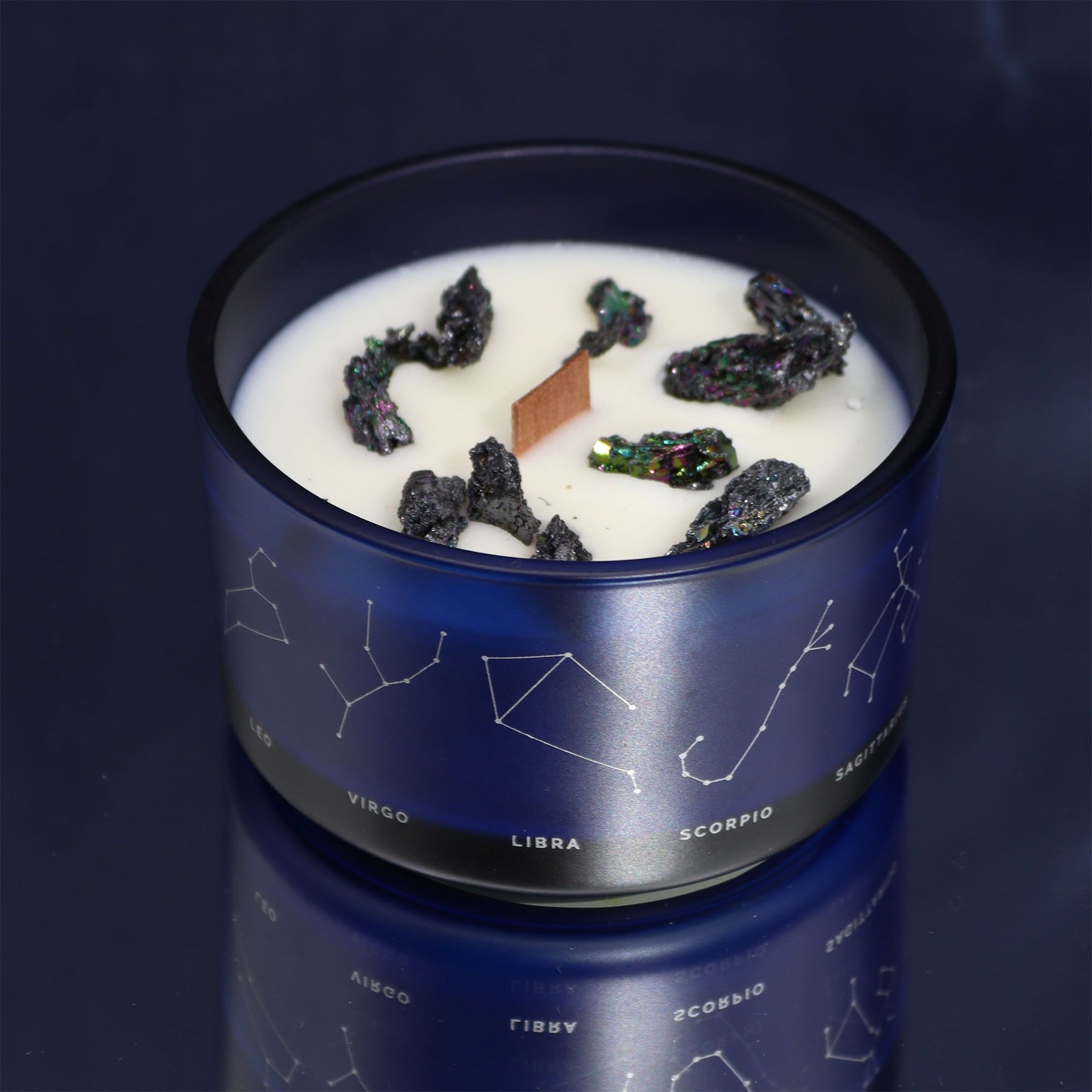 Candle in a blue container with star constellations on a dark background