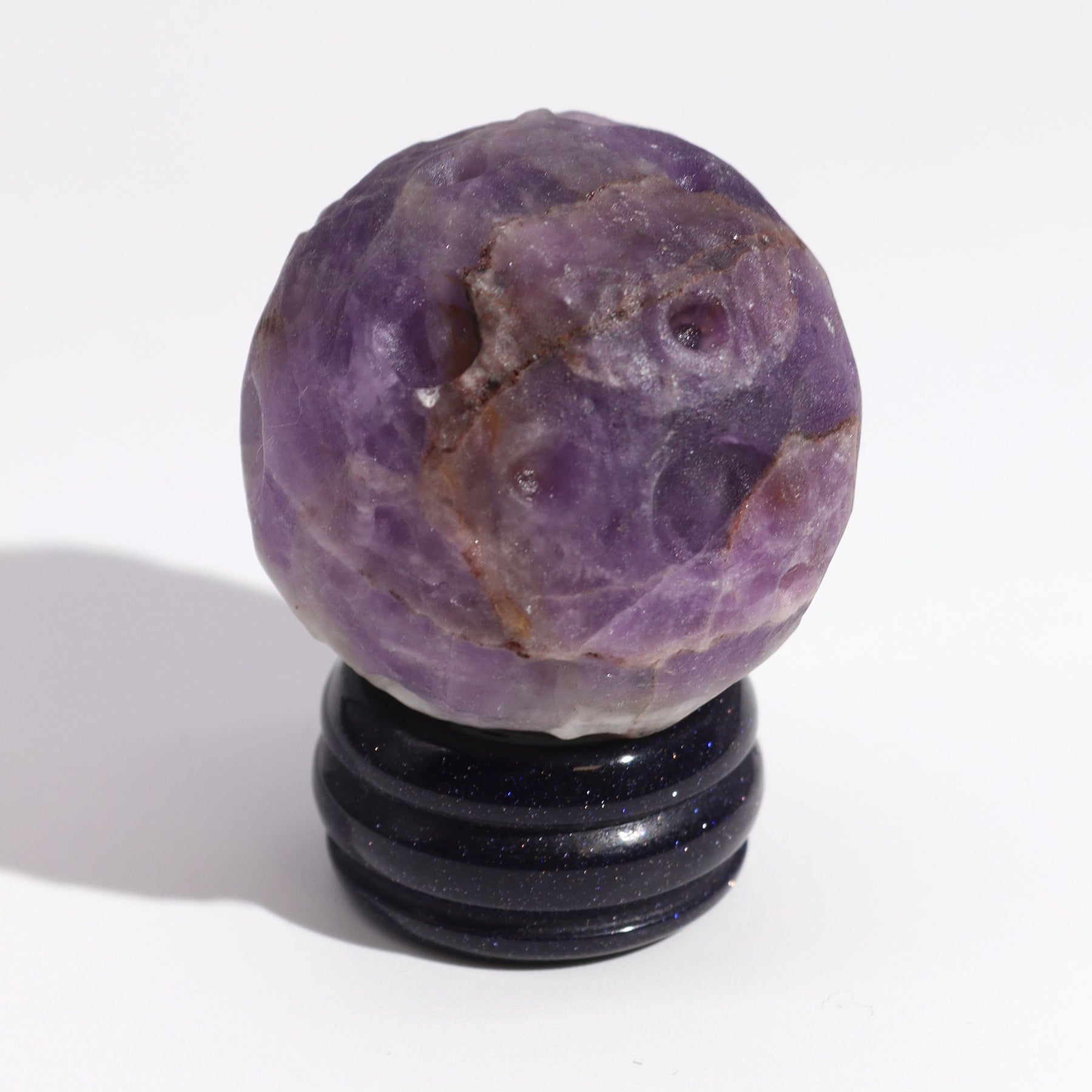 Rich purple 40mm Amethyst Jupiter sphere floating on glittering goldstone ring stand, regal cosmic background with soft golden light