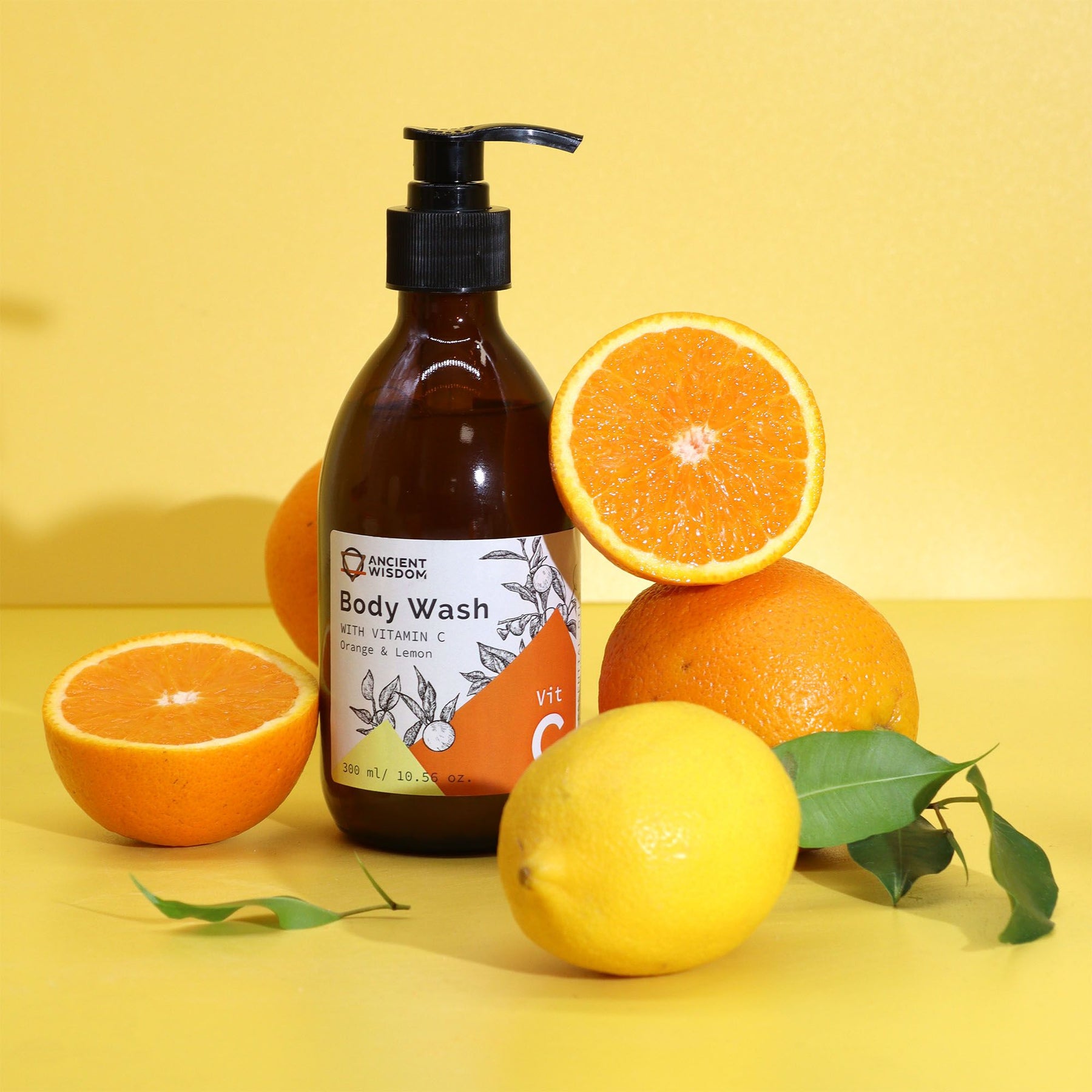 Body wash bottle with pump next to oranges and a lemon on a yellow background
