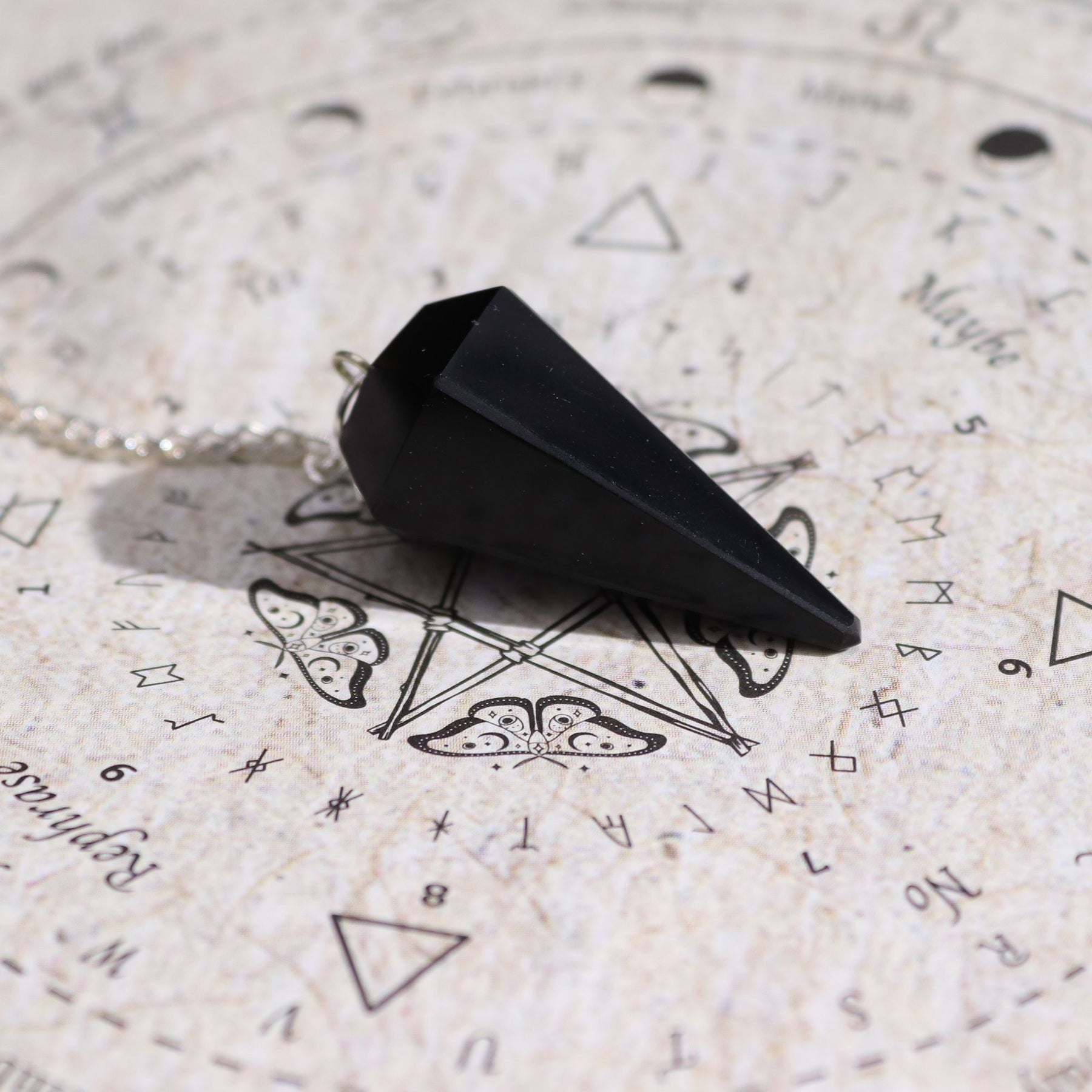Black pendulum on an astrological chart