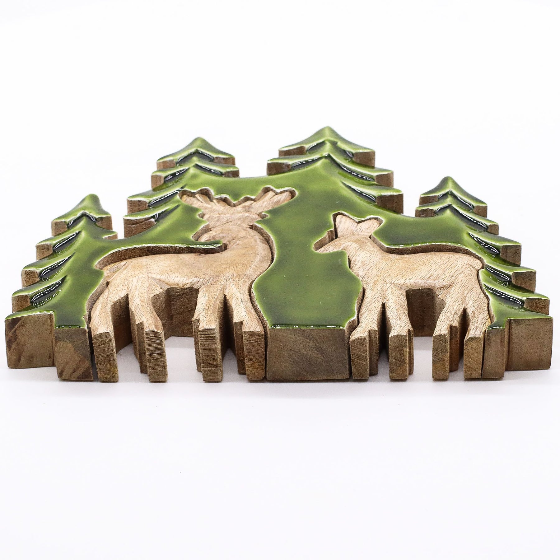 3D mango wood deer in forest decoration with two standing deer, green enamel trees and layered woodland scene on mantel with fairy lights and pine cones