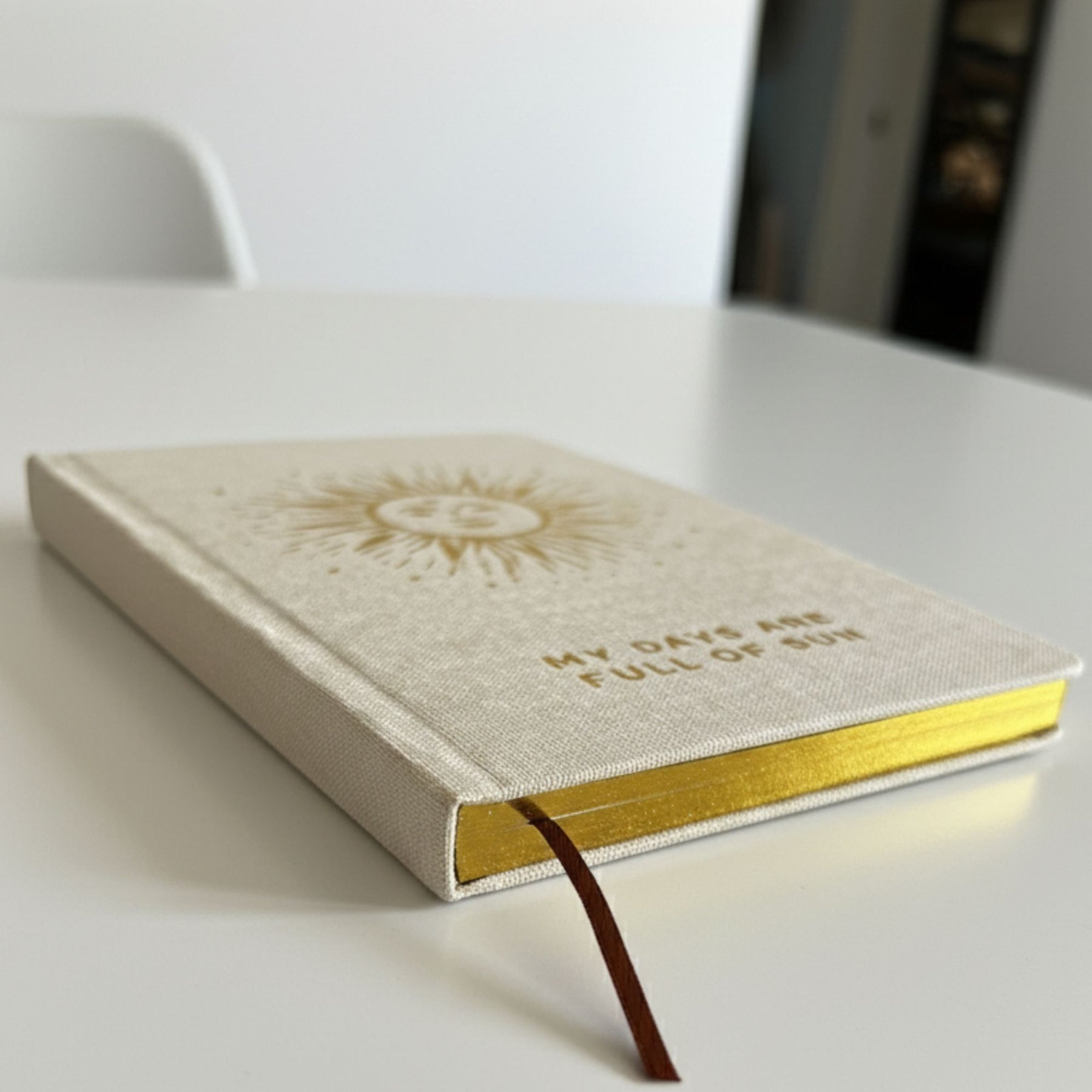 Creamy ivory gratitude journal with gleaming gold sun design and gilded page edges