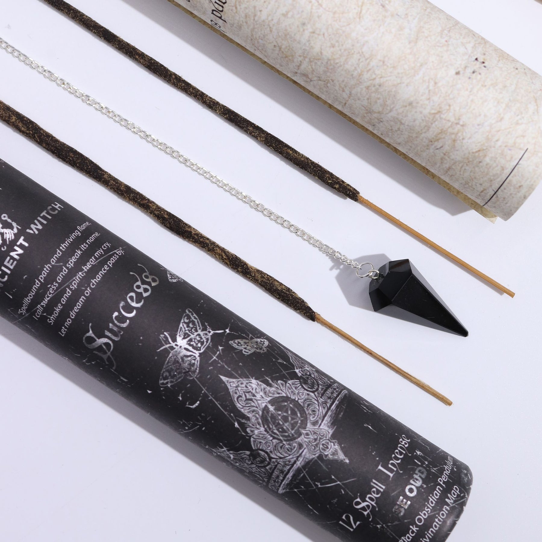 Incense sticks with packaging and a black crystal pendulum on a white background