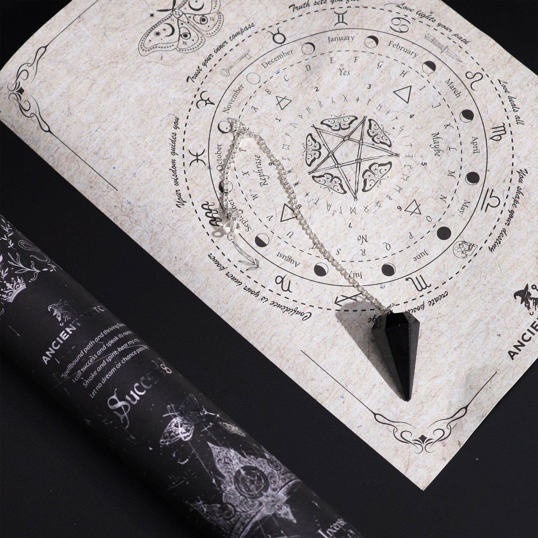 A decorative paper with astrological symbols and a black pendulum on a dark surface.