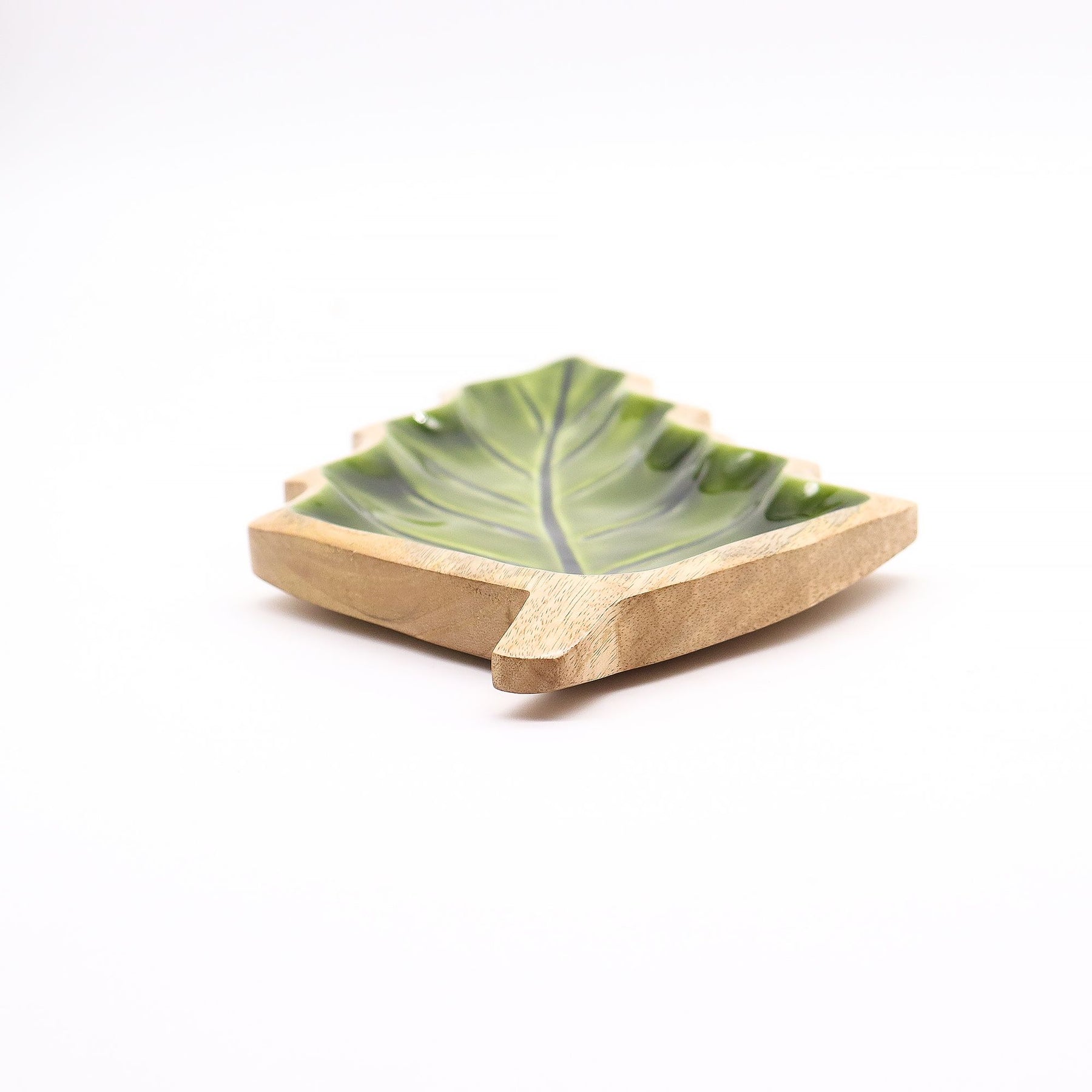 Large leaf-shaped mango wood bowl with rich green enamel inside, filled with pine cones and candles on autumn table setting
