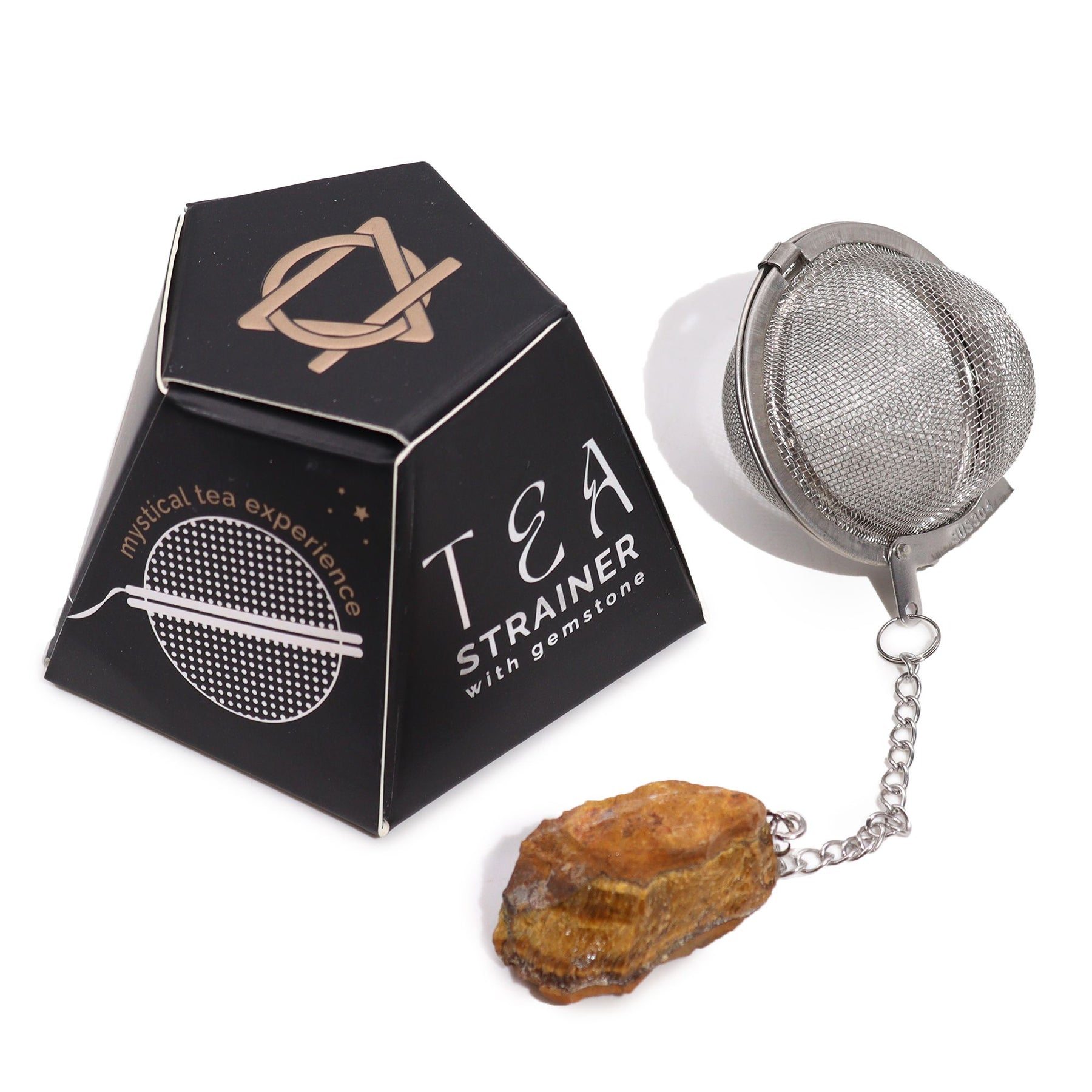 Tea strainer with gemstone next to its packaging on a white background