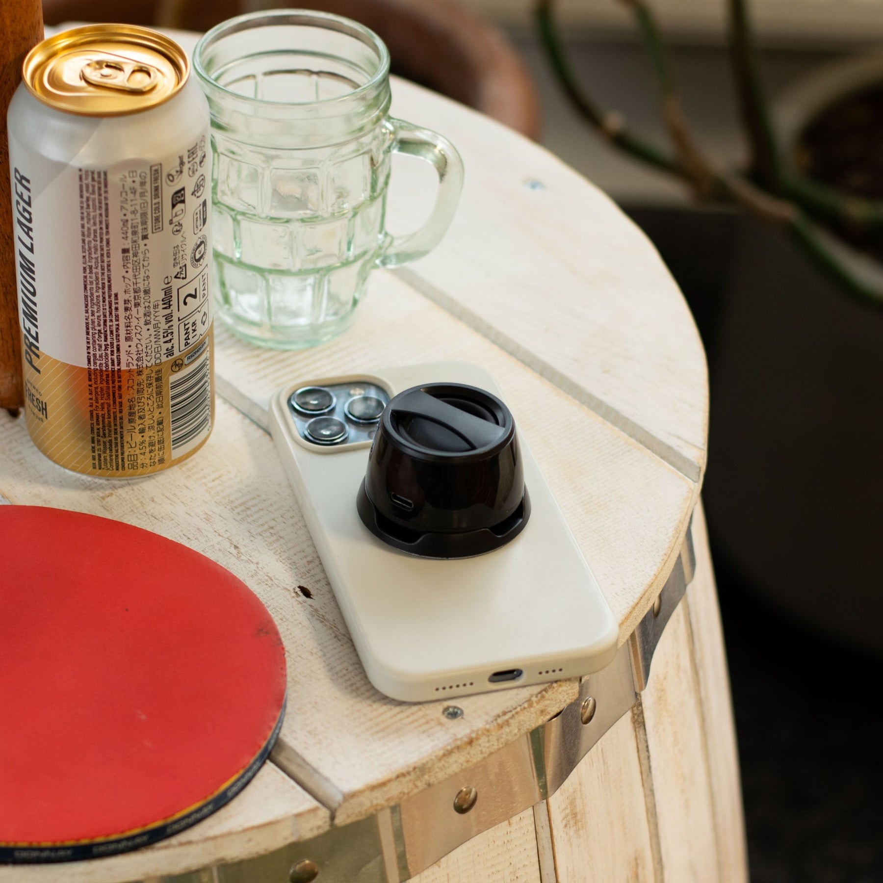 G300 magnetic mini speaker in sleek black attached to iPhone back via MagSafe, playing music with subtle LED glow, acting as phone stand on desk