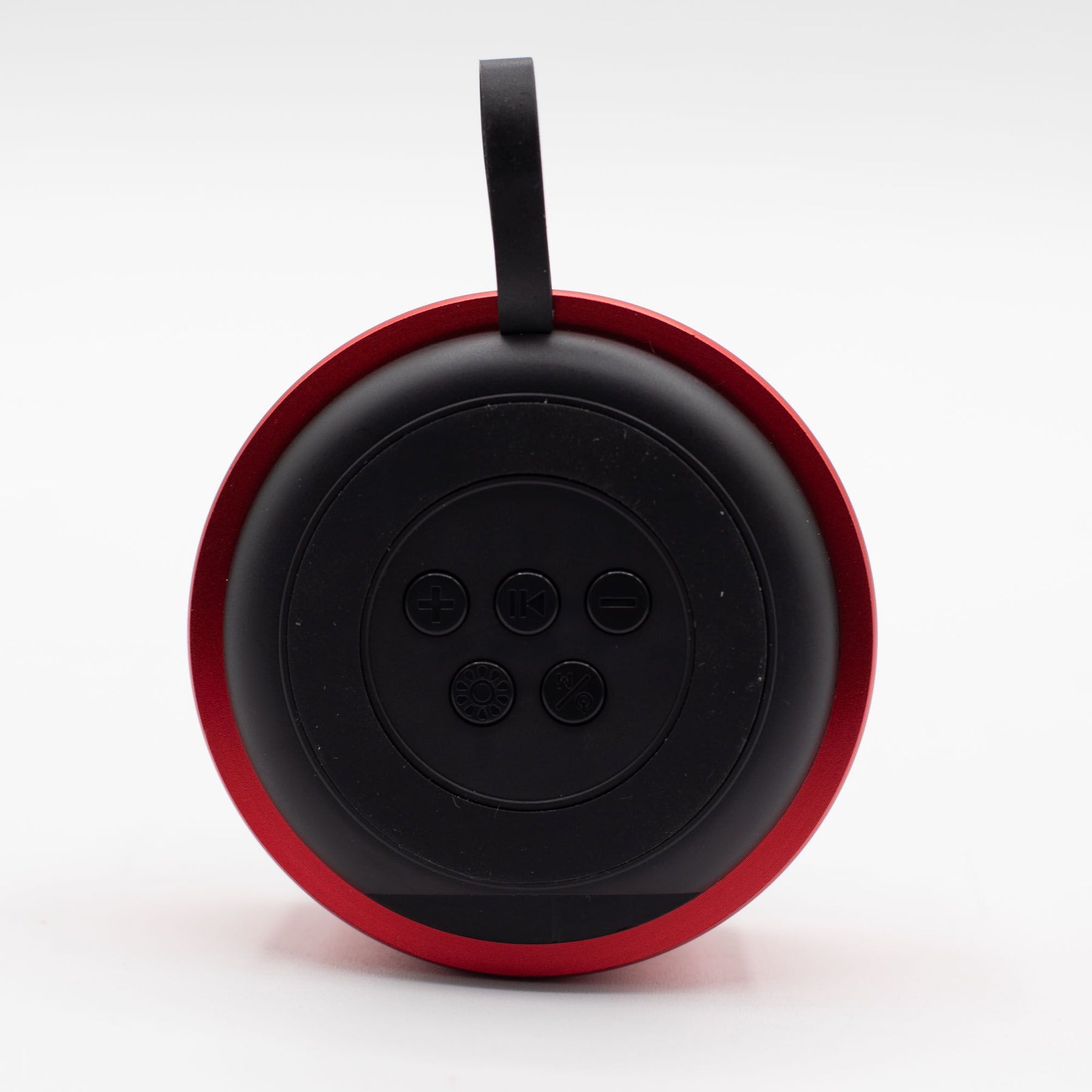 Close-up of red mini speaker showing mandala-style LED illumination pulsing in sync with music, speaker grille and top controls detail