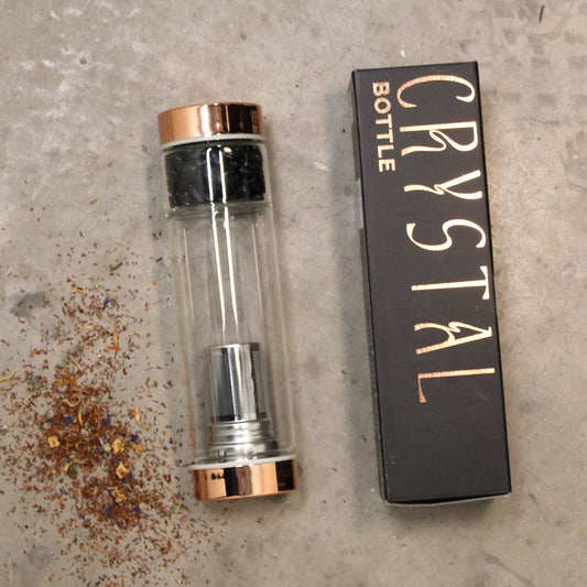 Rose gold amethyst crystal tea infuser bottle with removable bottom chamber full of purple amethyst chips, neoprene sleeve, loose leaf tea and steaming brew