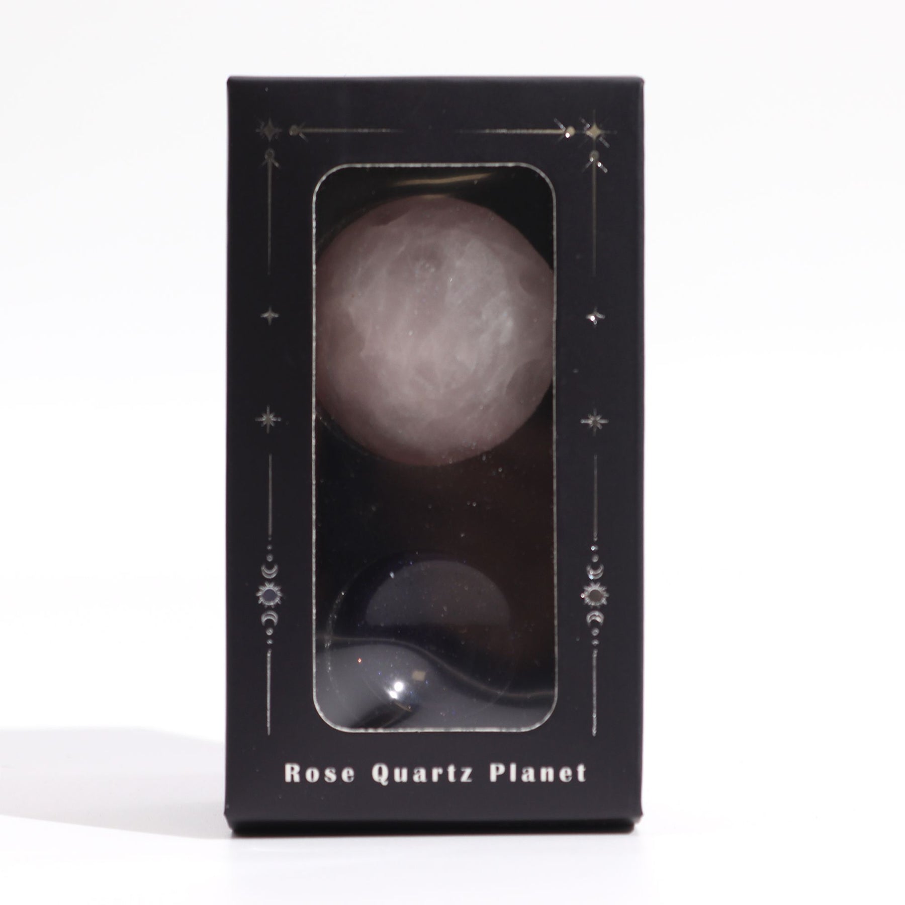 Soft pink 40mm Rose Quartz Venus sphere glowing on glittering goldstone ring stand, surrounded by rose petals and candles in romantic setting