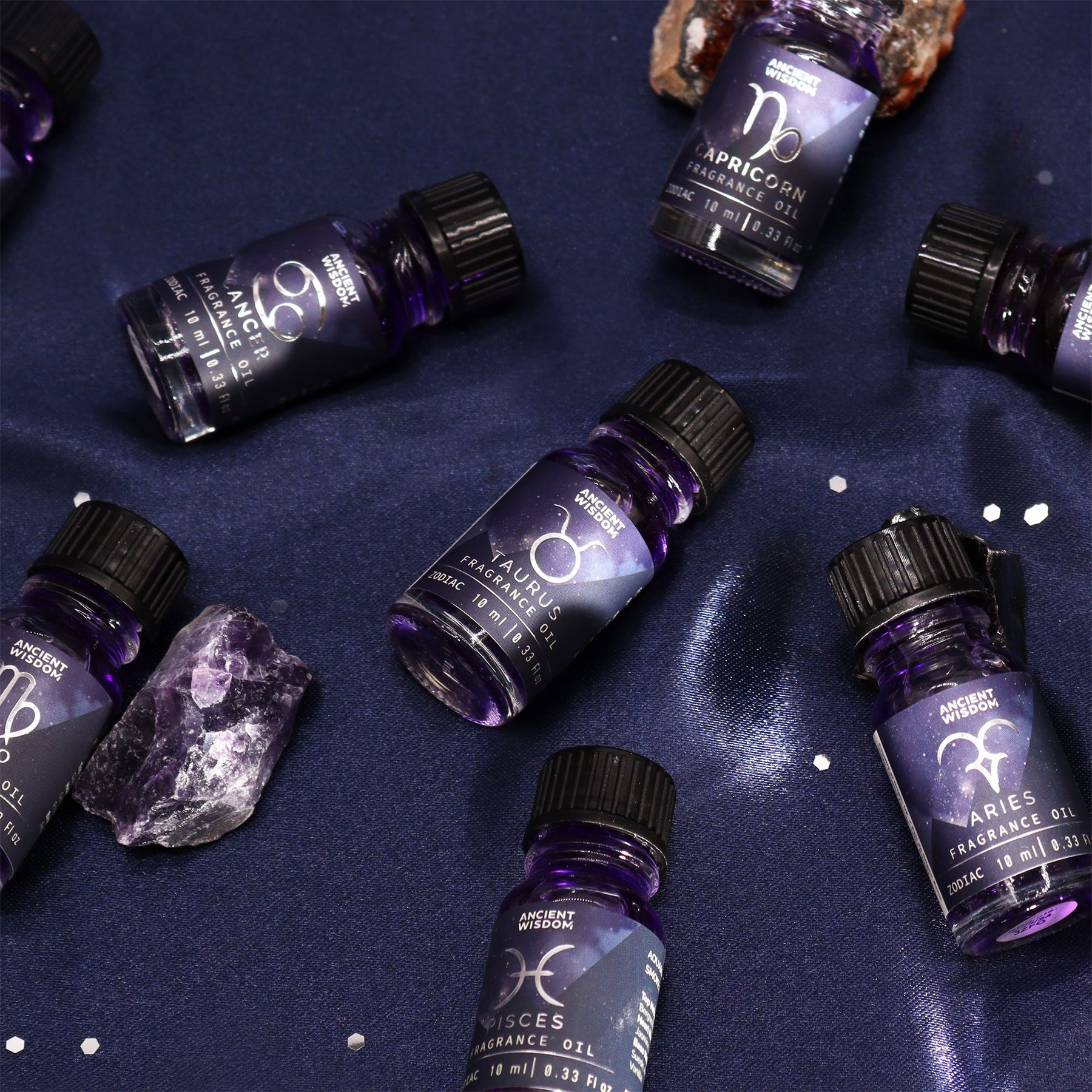 Aromatherapy oil bottles with zodiac symbols on a dark blue background