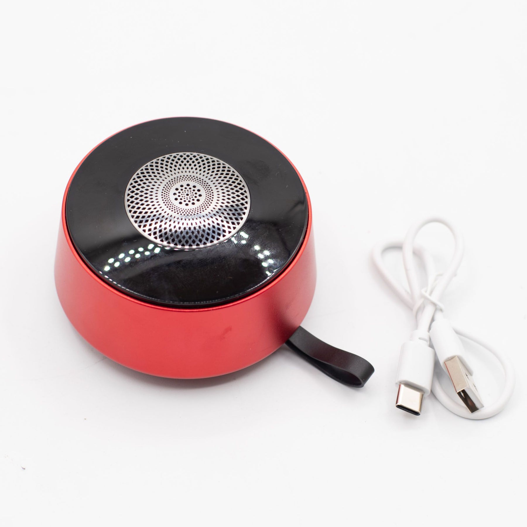 Mini speaker charging via USB cable, 600mAh battery indicator visible, travel-ready compact size