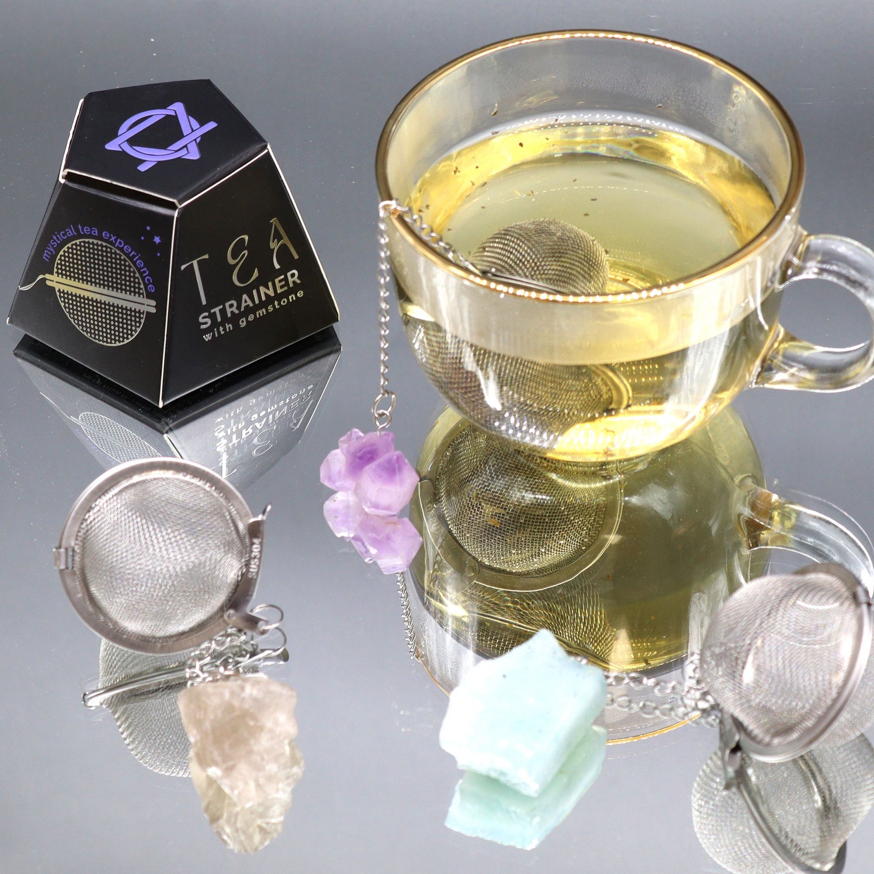 Tea strainers with a glass of tea on a reflective surface