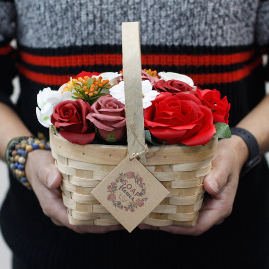 Person holding a basket of soap flowers with a visible brand tag.