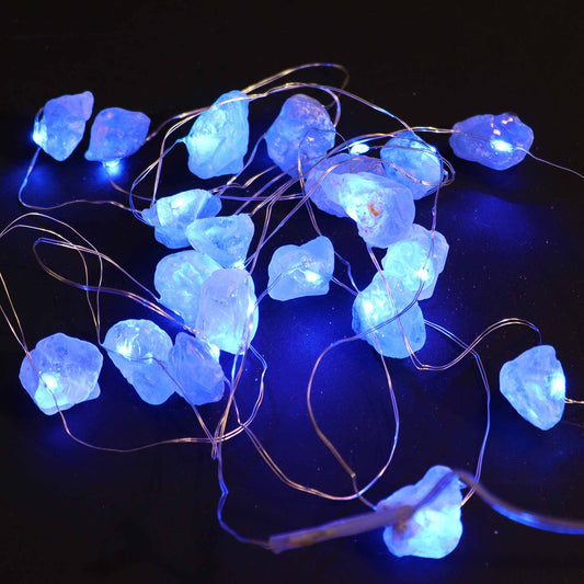 Celestite crystal fairy lights glowing soft blue in a glass jar on bedside table with moon and stars in dreamy bedroom setting