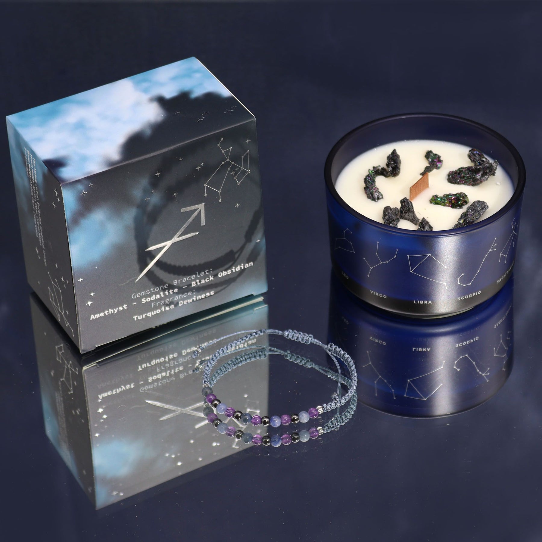 Candle with blue packaging and bracelet on a reflective surface