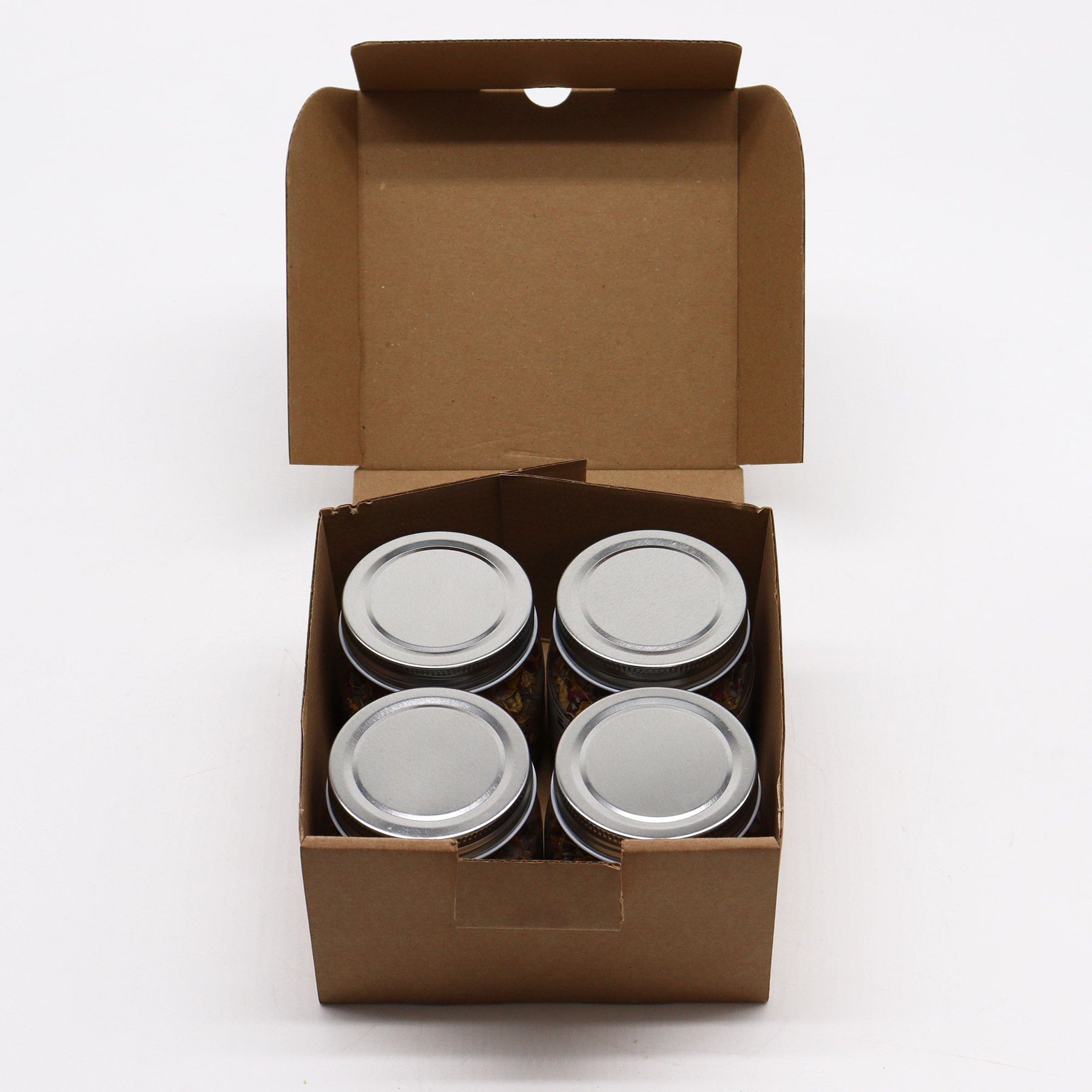 Four metal cans in a brown cardboard box on a white background