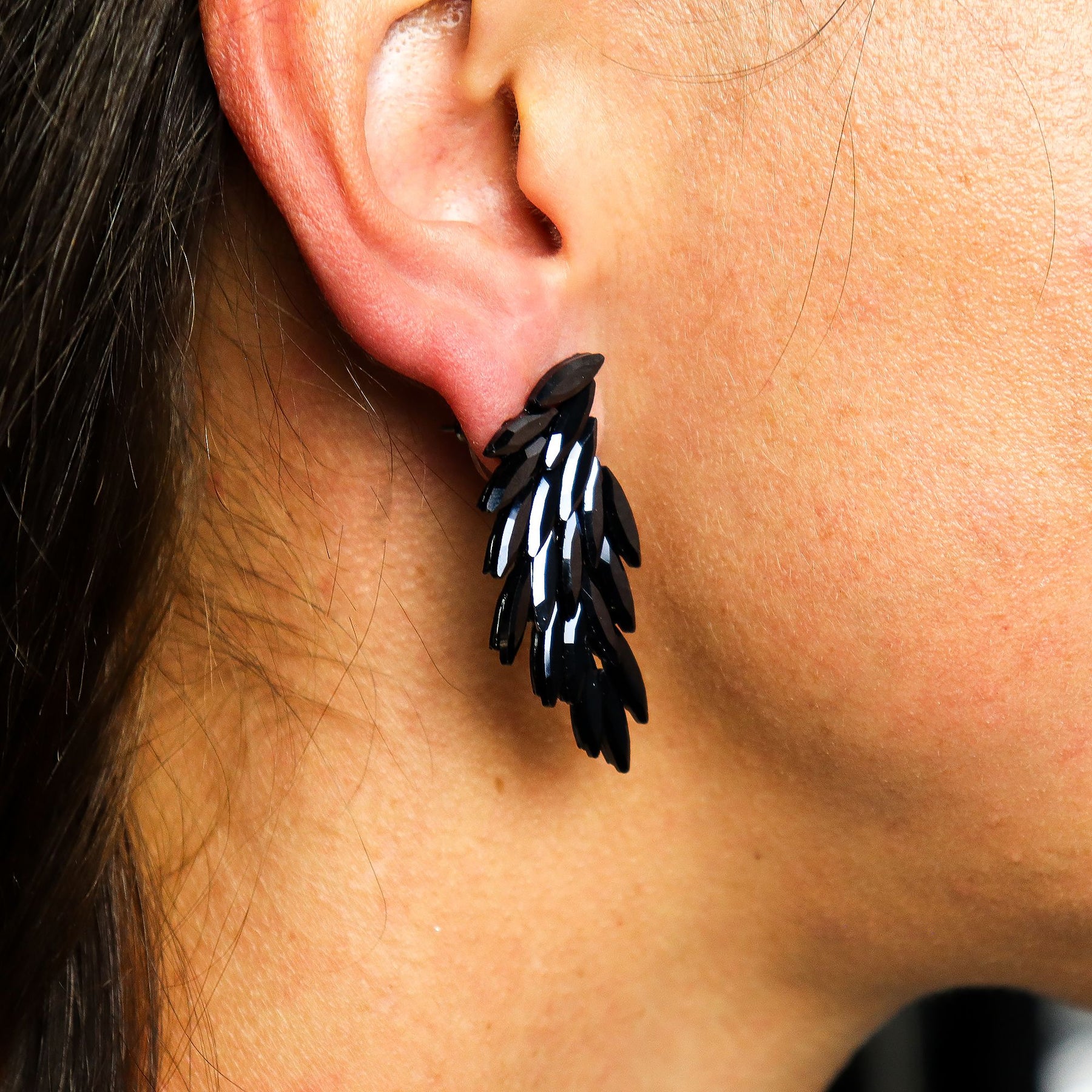Close-up of an ear wearing a black and white feather-shaped earring.