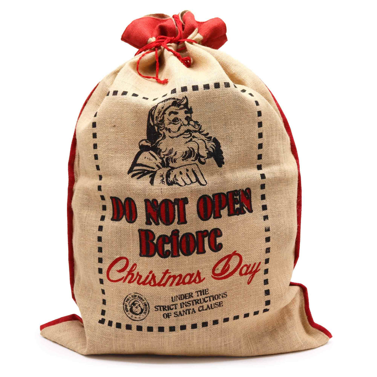 Large natural jute Christmas sack with bold “Do Not Open Before Christmas Day” print, overflowing with wrapped gifts, red ribbon tie and twinkling lights