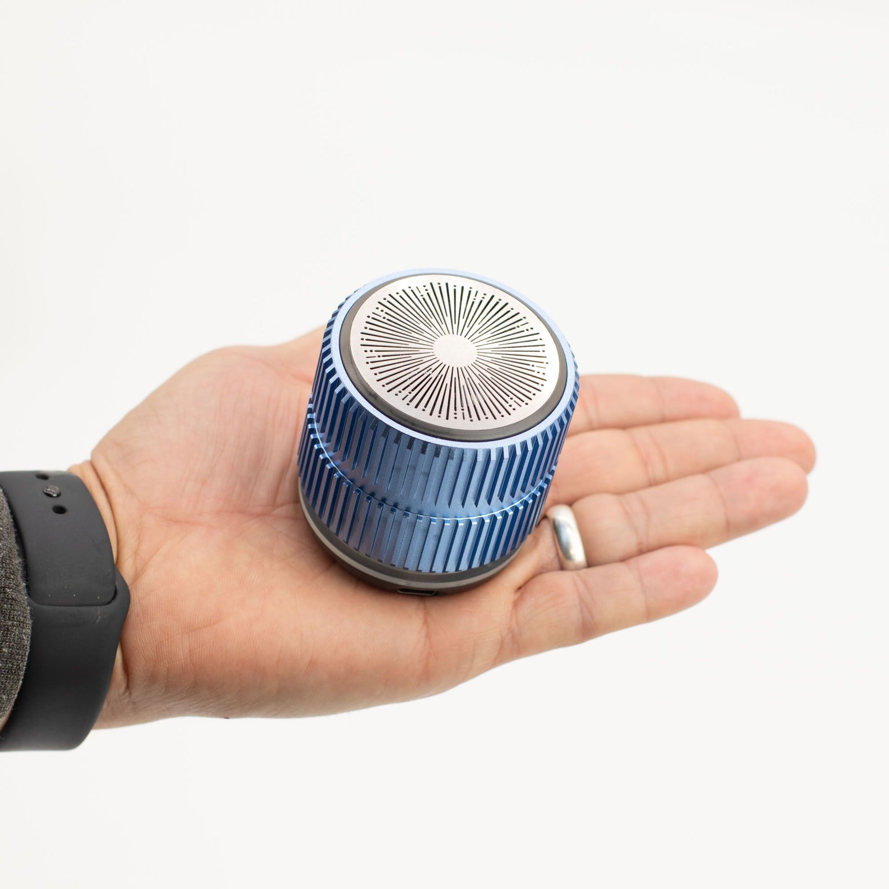 Speaker in hand demonstrating ultra-portable 130g weight and 55×59mm size for easy carry