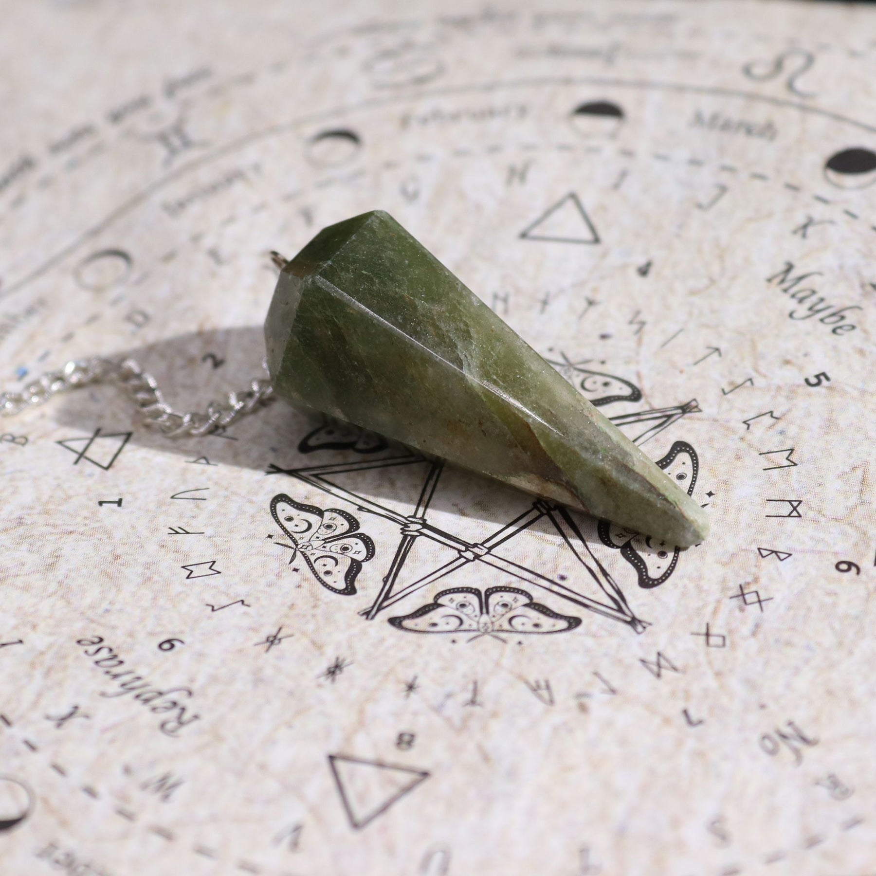 Green stone pendulum on an astrological chart