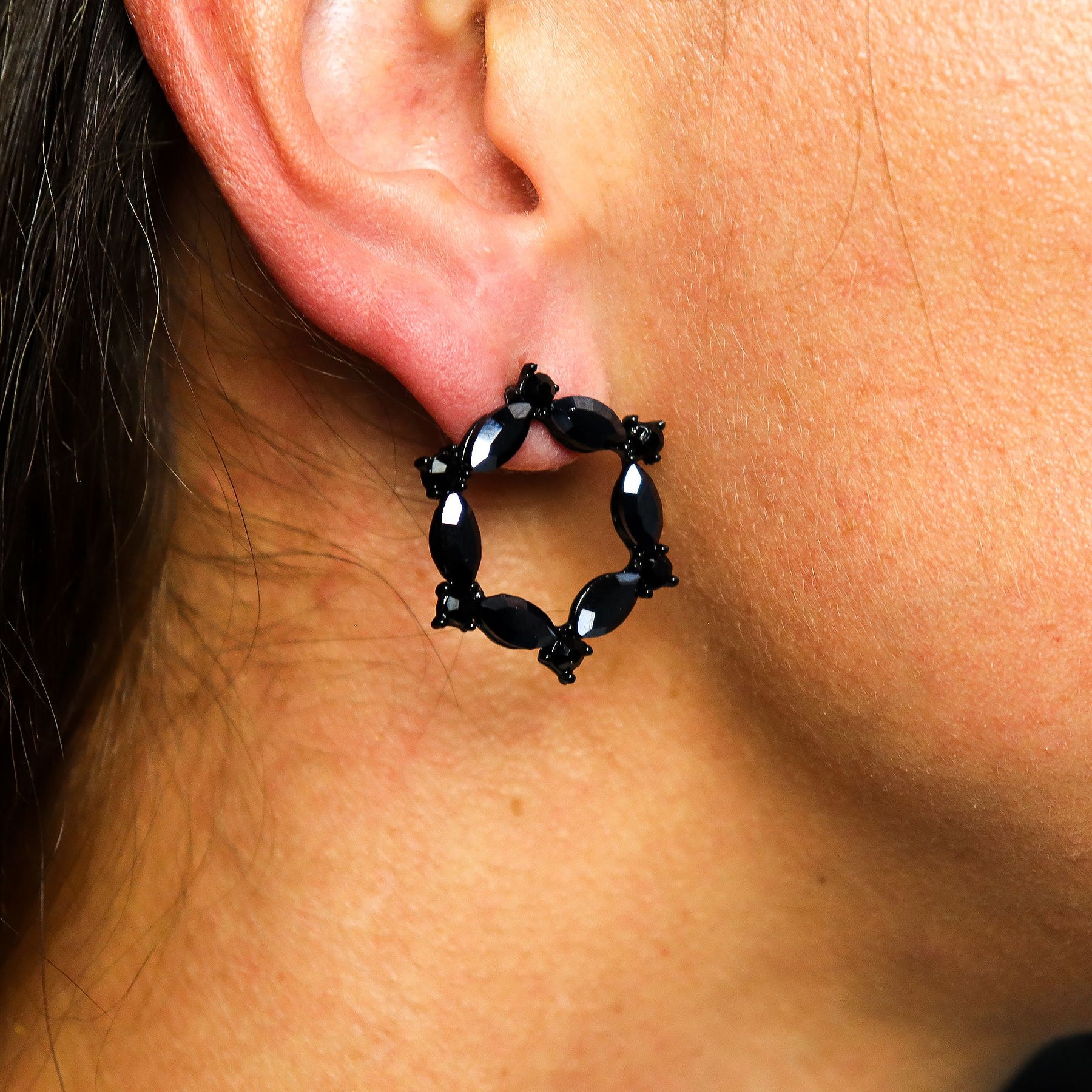 Close-up of a black hoop earring worn on an ear.