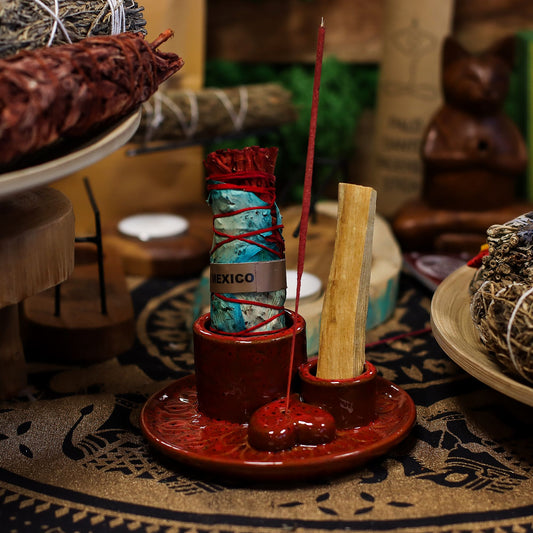 Glossy red ceramic mandala smudge holder with heart-shaped incense dish, Palo Santo stick burning, sage bundle on altar setting