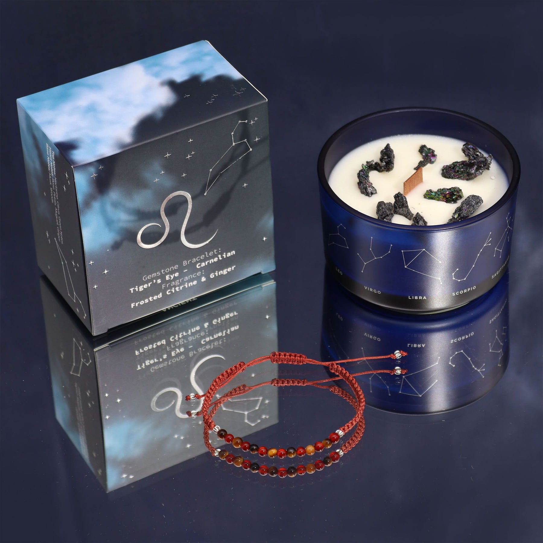 Candle with packaging and red bracelets on a reflective surface