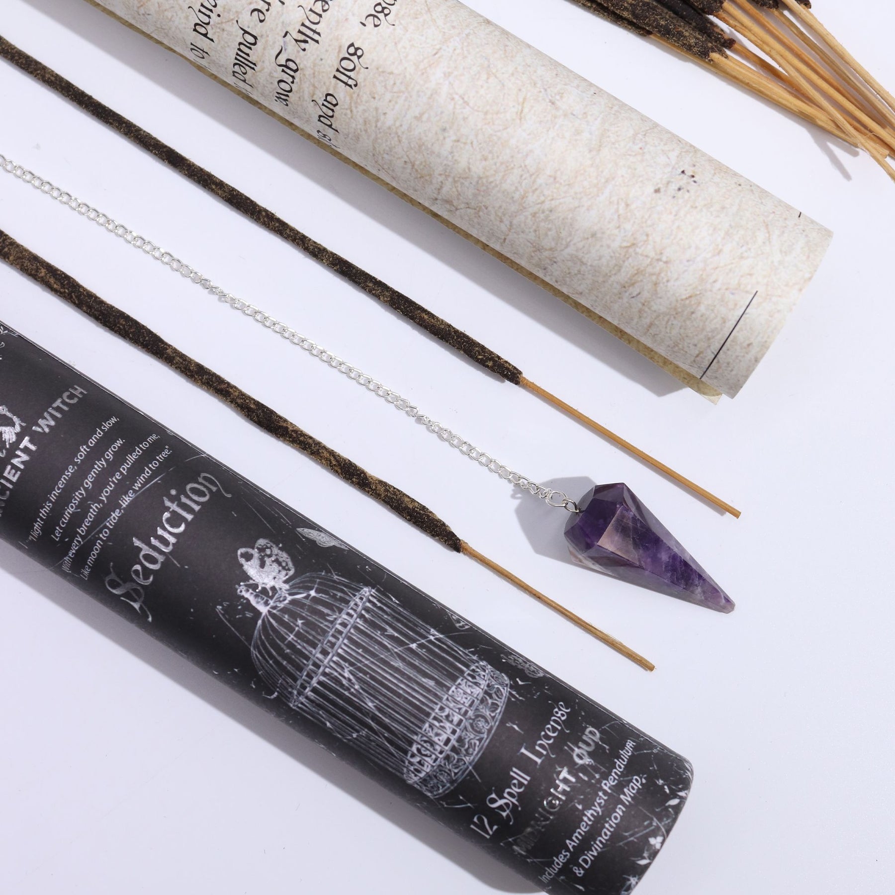 Incense sticks with packaging and a pendulum crystal on a white background