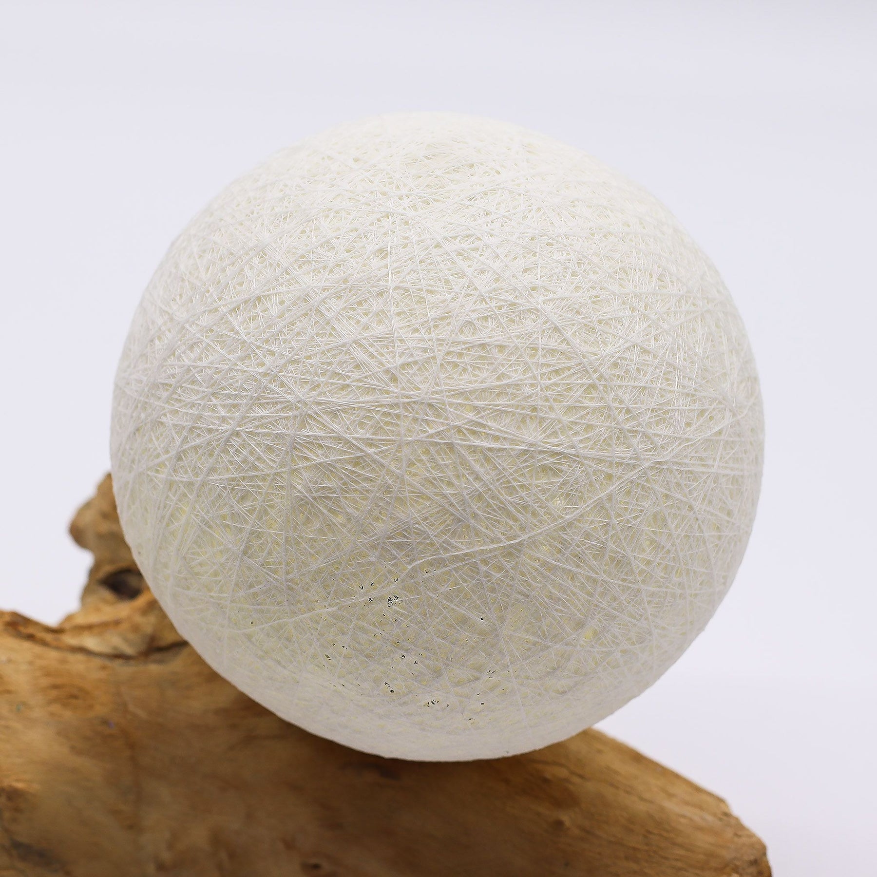 Ivory cotton-wrapped Luna sphere glowing like a full moon atop twisted driftwood base