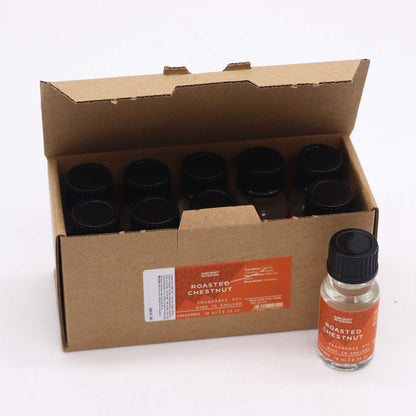 10ml amber glass bottle of Roasted Chestnut fragrance oil with chestnuts and glowing fireplace in cosy winter background