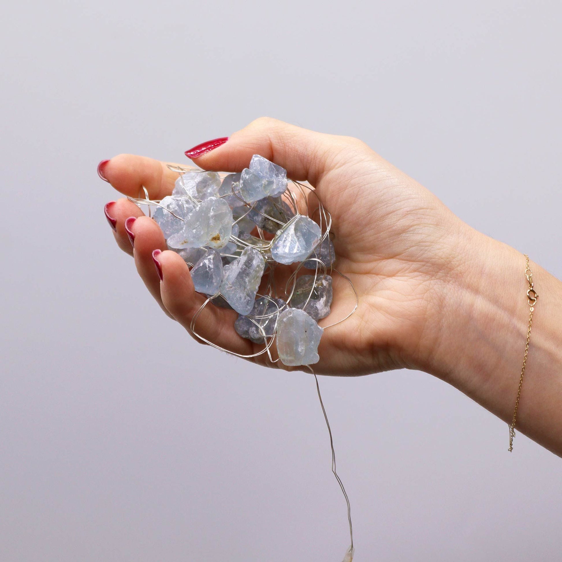 Celestite crystal fairy lights glowing soft blue in a glass jar on bedside table with moon and stars in dreamy bedroom setting