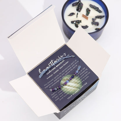Box of gemstone bracelets with a candle featuring crystals on a white background
