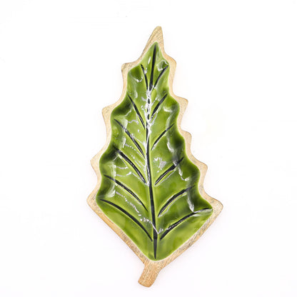 Large leaf-shaped mango wood bowl with rich green enamel inside, filled with pine cones and candles on autumn table setting