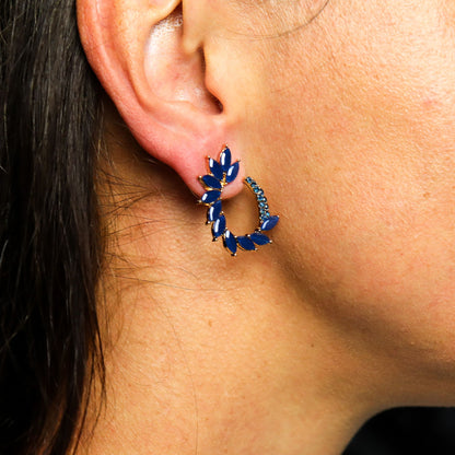Close-up of an ear wearing a blue gemstone hoop earring.