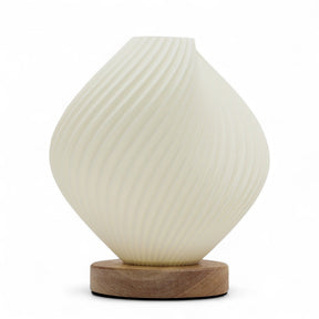 Shell Twisted New Wave USB lamp with textured honeycomb surface and elegant twisted shell-inspired shape, warm glow on 3rd brightness setting, placed on wooden base