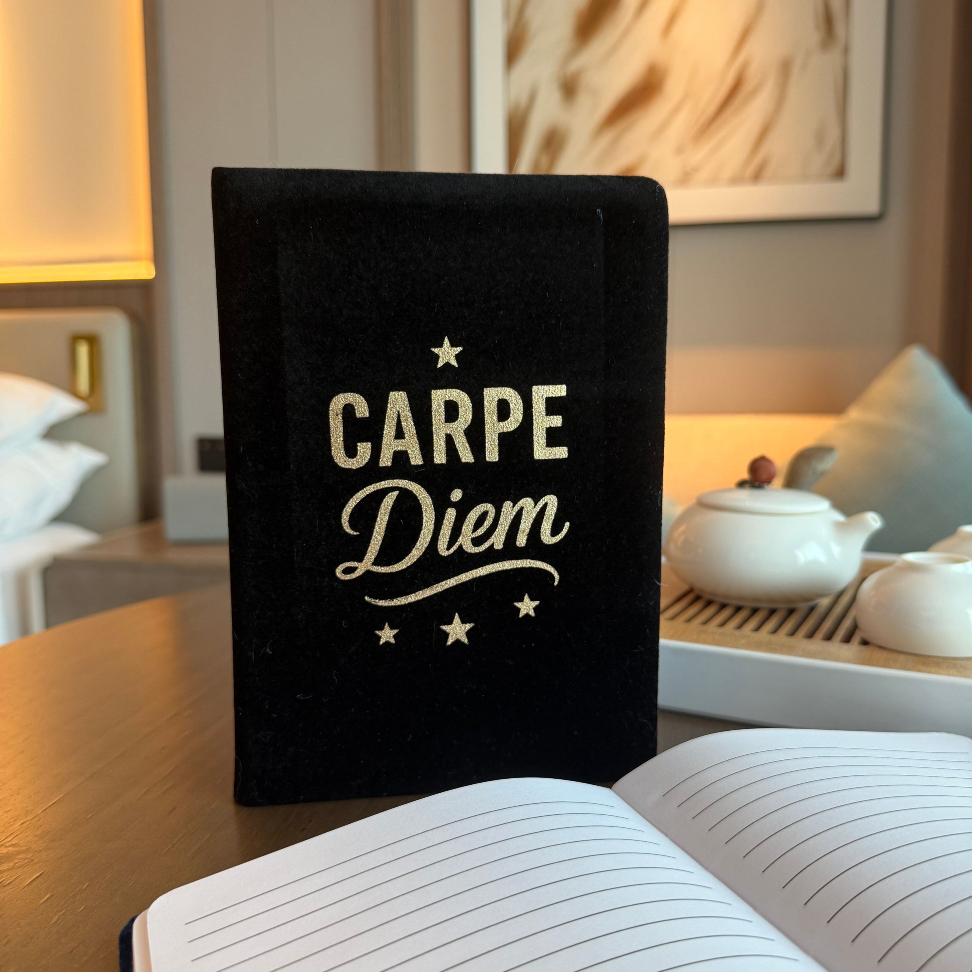 Black notebook with 'Carpe Diem' on a table in a room setting