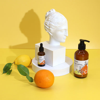 Cosmetic products on a yellow background with a classical bust and citrus fruits.