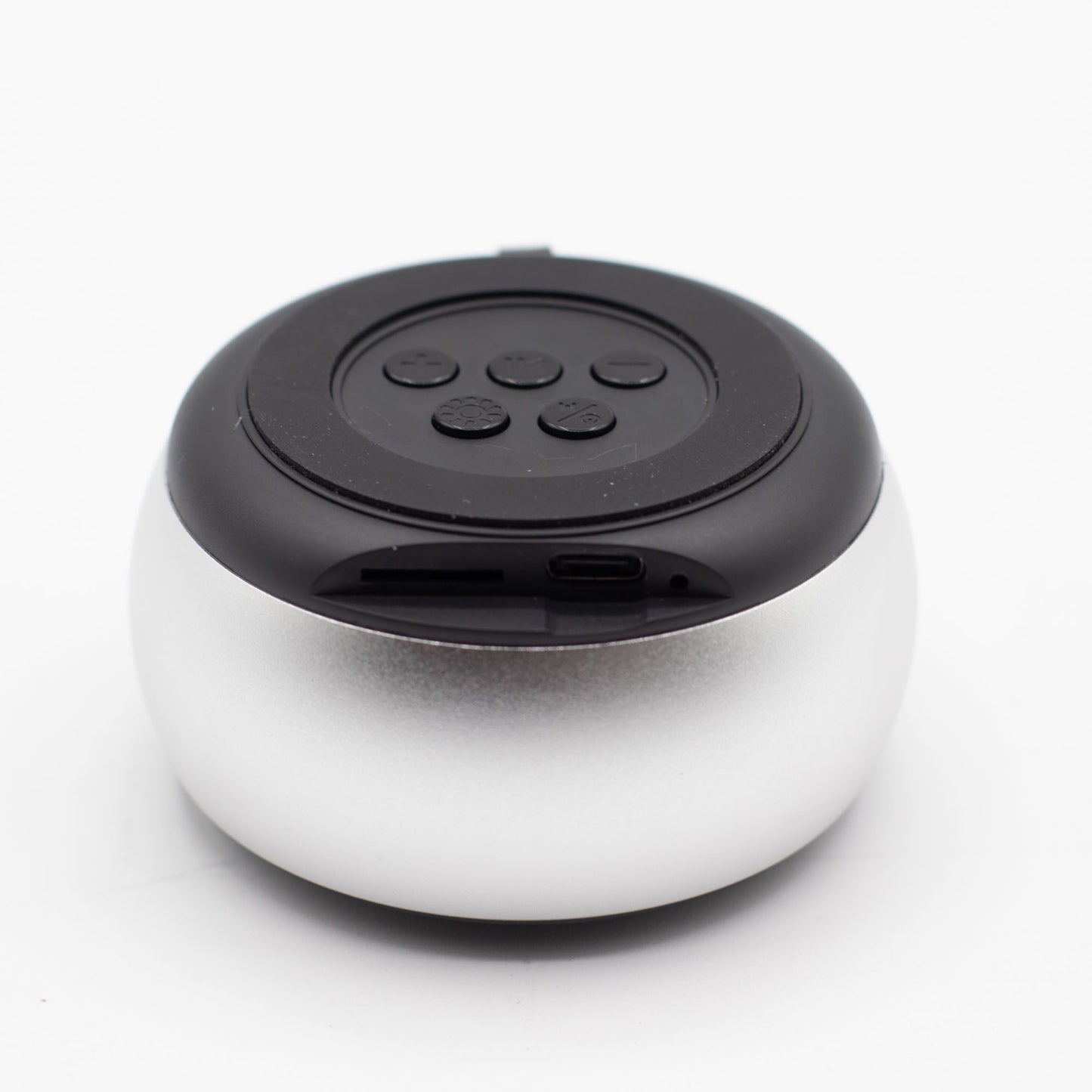 Close-up of silver mini speaker showing mandala-style LED illumination, top controls and speaker grille detail