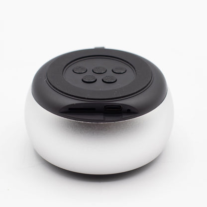 Close-up of silver mini speaker showing mandala-style LED illumination, top controls and speaker grille detail