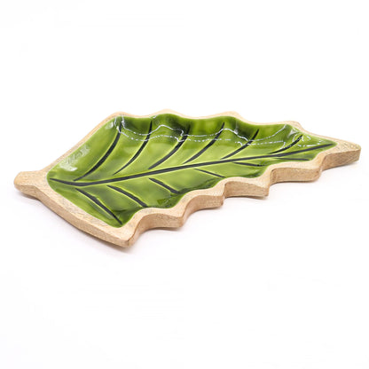 Large leaf-shaped mango wood bowl with rich green enamel inside, filled with pine cones and candles on autumn table setting
