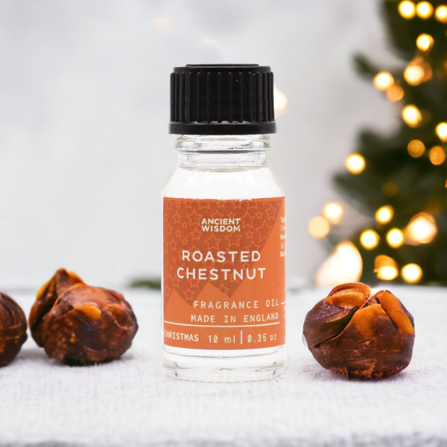 10ml amber glass bottle of Roasted Chestnut fragrance oil with chestnuts and glowing fireplace in cosy winter background