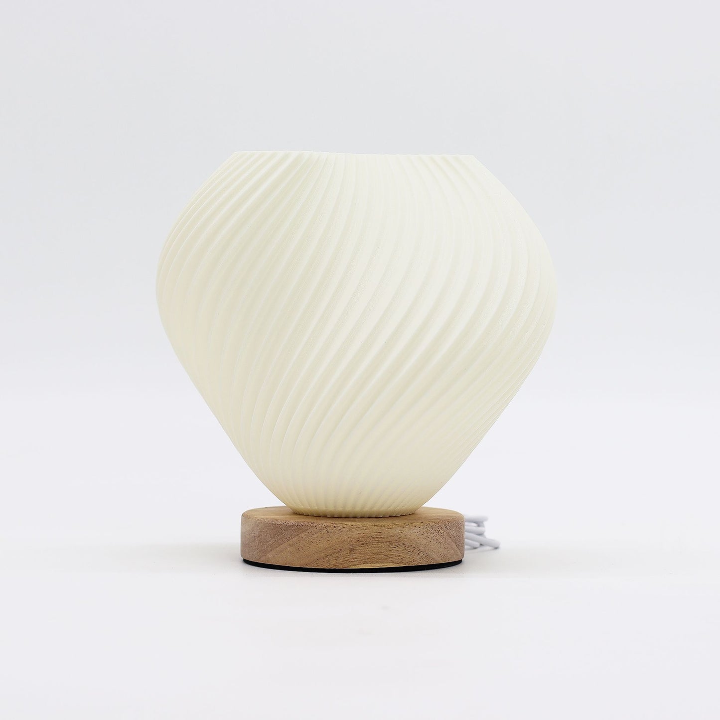 Shell Twisted New Wave USB lamp with textured honeycomb surface and elegant twisted shell-inspired shape, warm glow on 3rd brightness setting, placed on wooden base