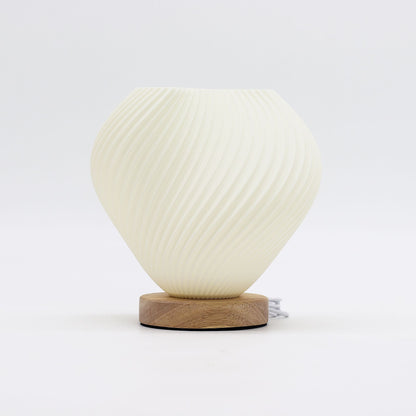 Shell Twisted New Wave USB lamp with textured honeycomb surface and elegant twisted shell-inspired shape, warm glow on 3rd brightness setting, placed on wooden base
